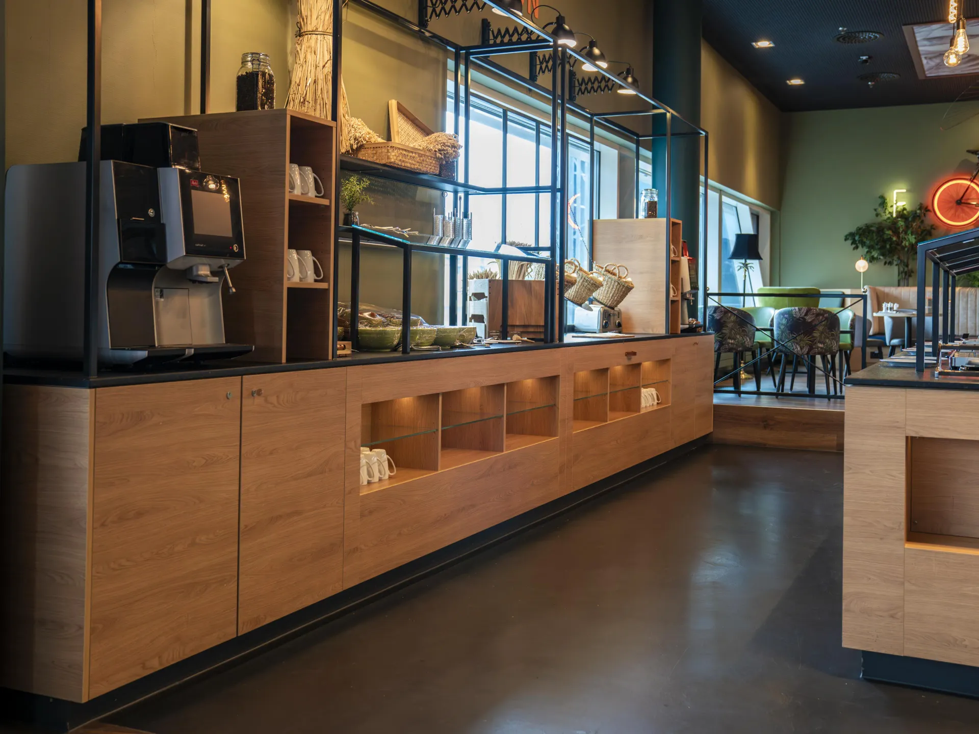 Oak buffet counter with black steel display shelving and integrated coffee machine in restaurant.