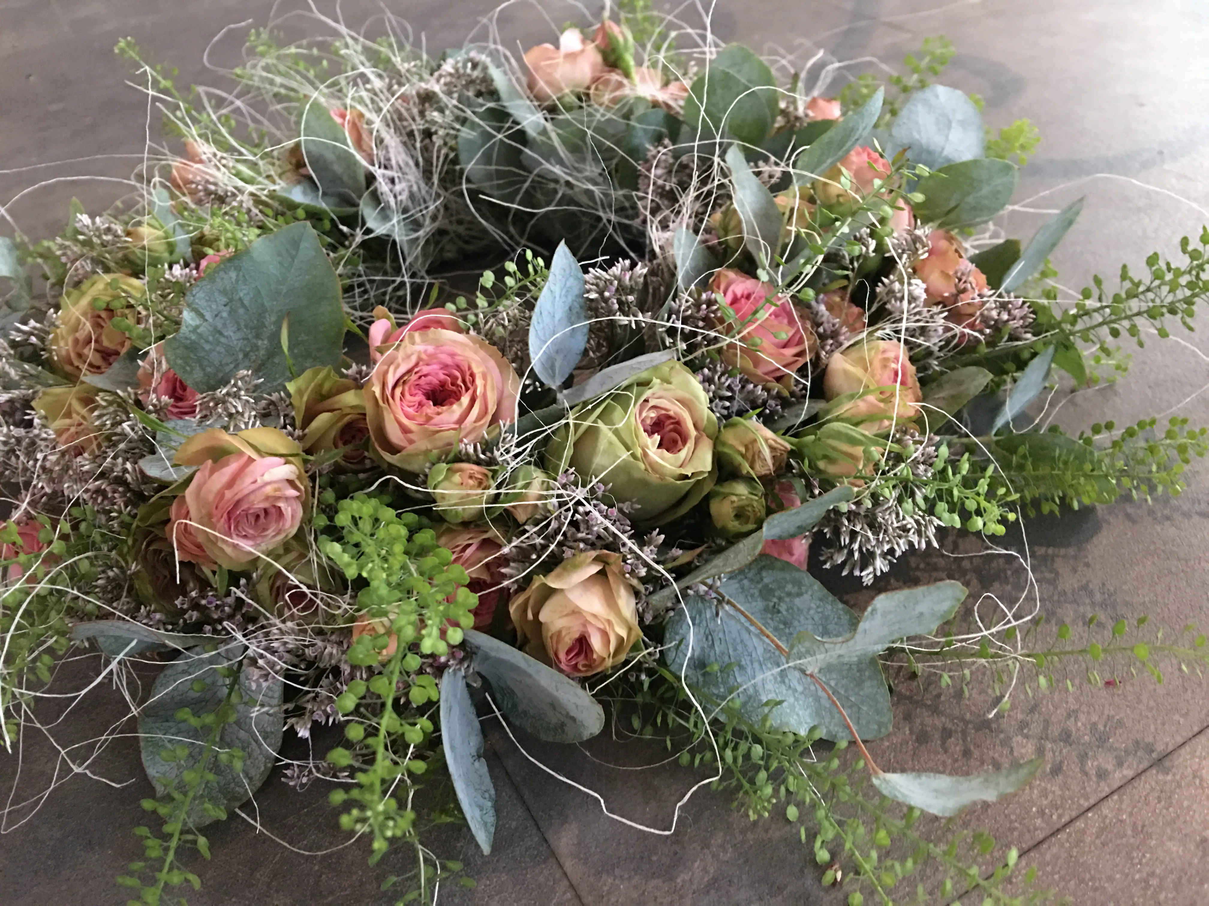 A rustic wooden board centerpiece with a purple candle, dried hydrangeas, moss, and eucalyptus.
