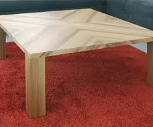 Handcrafted wooden coffee table with geometric parquet-style top on a red carpet.
