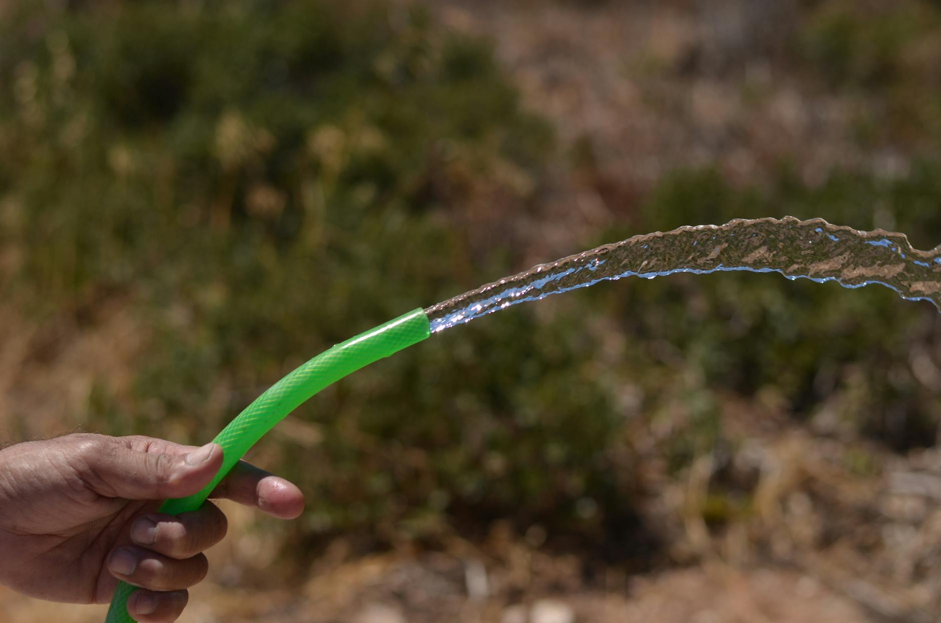 Eine moderne Schweizer Einfamilienhausfassade mit Regenrinne, die in eine grosse Regentonne im Garten führt, um Regenwasser für die nachhaltige Bewässerung zu sammeln.
