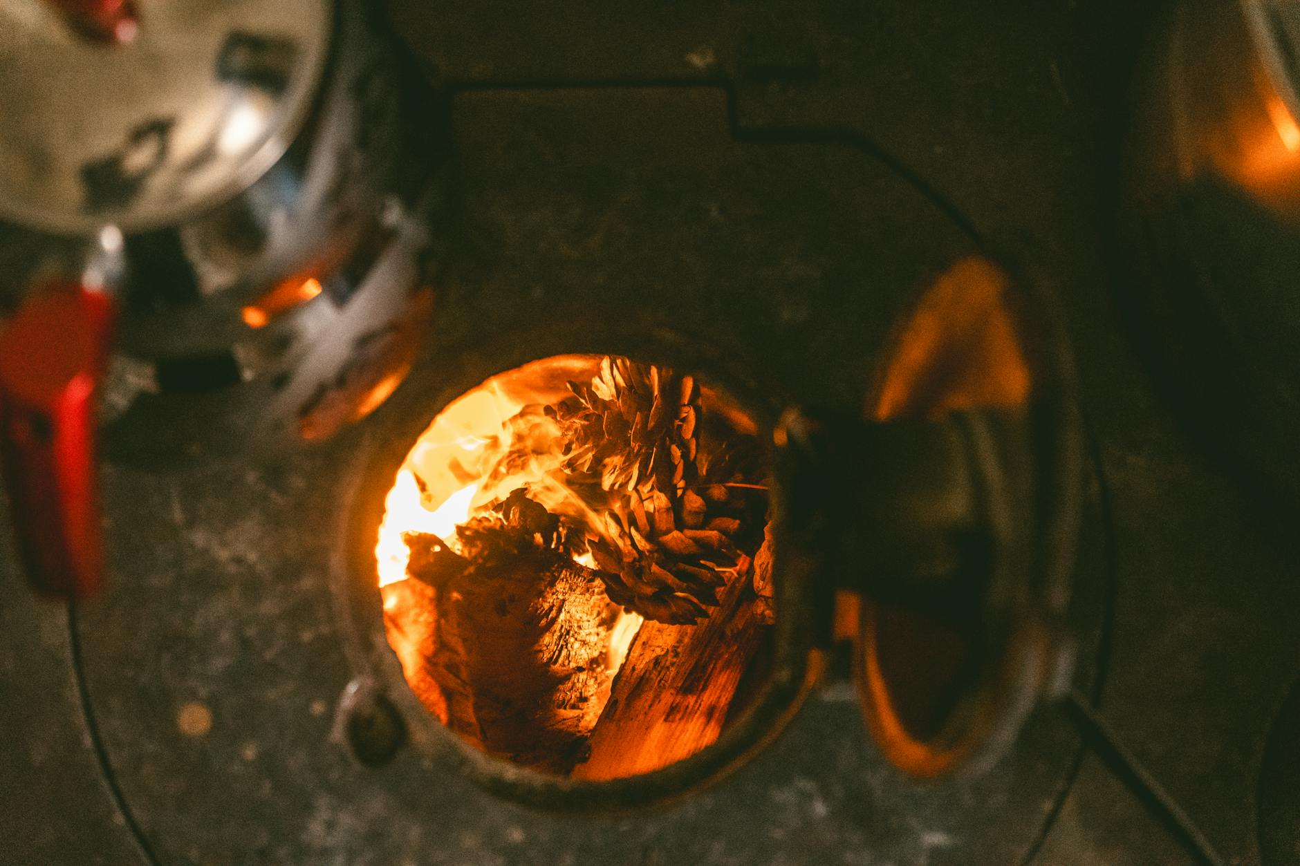 Ein moderner Holzofen in einer schweizerischen Wohnstube mit trockenem Brennholz daneben, symbolisiert umweltfreundliches und gesetzeskonformes Heizen.