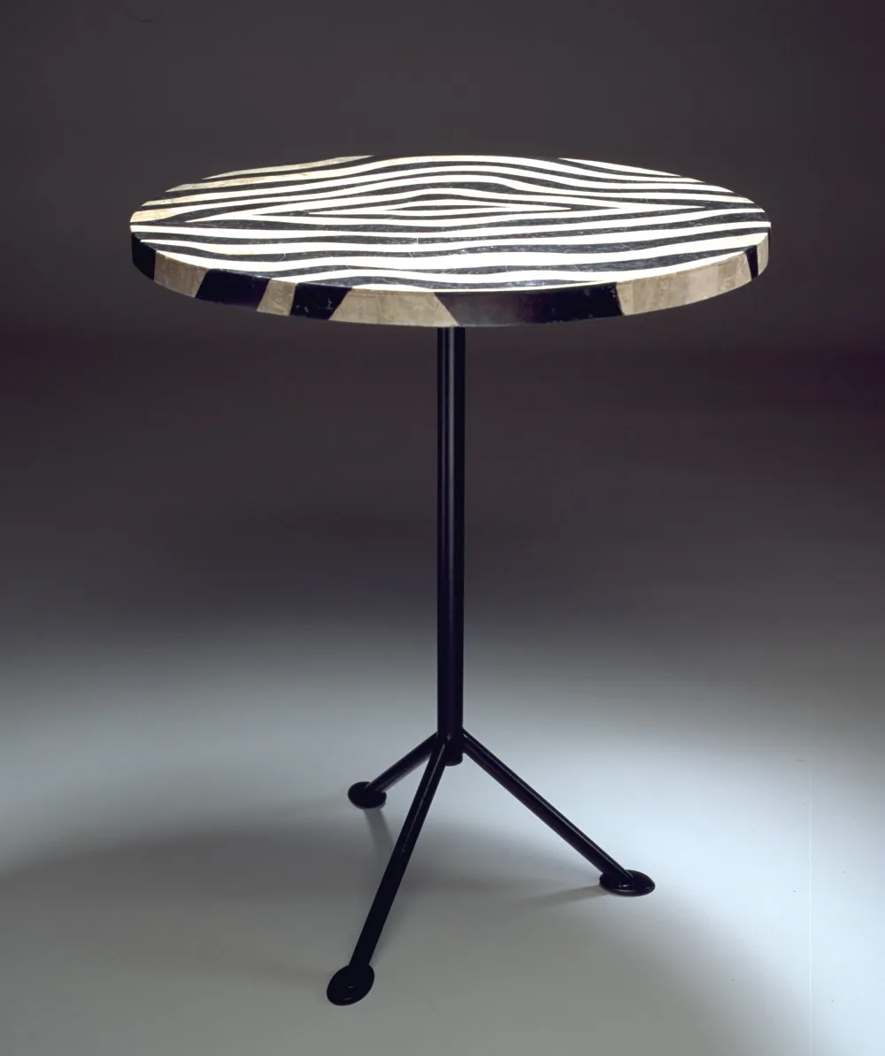 Round side table with zebra-striped stone top on black tripod base, front view showing full height.