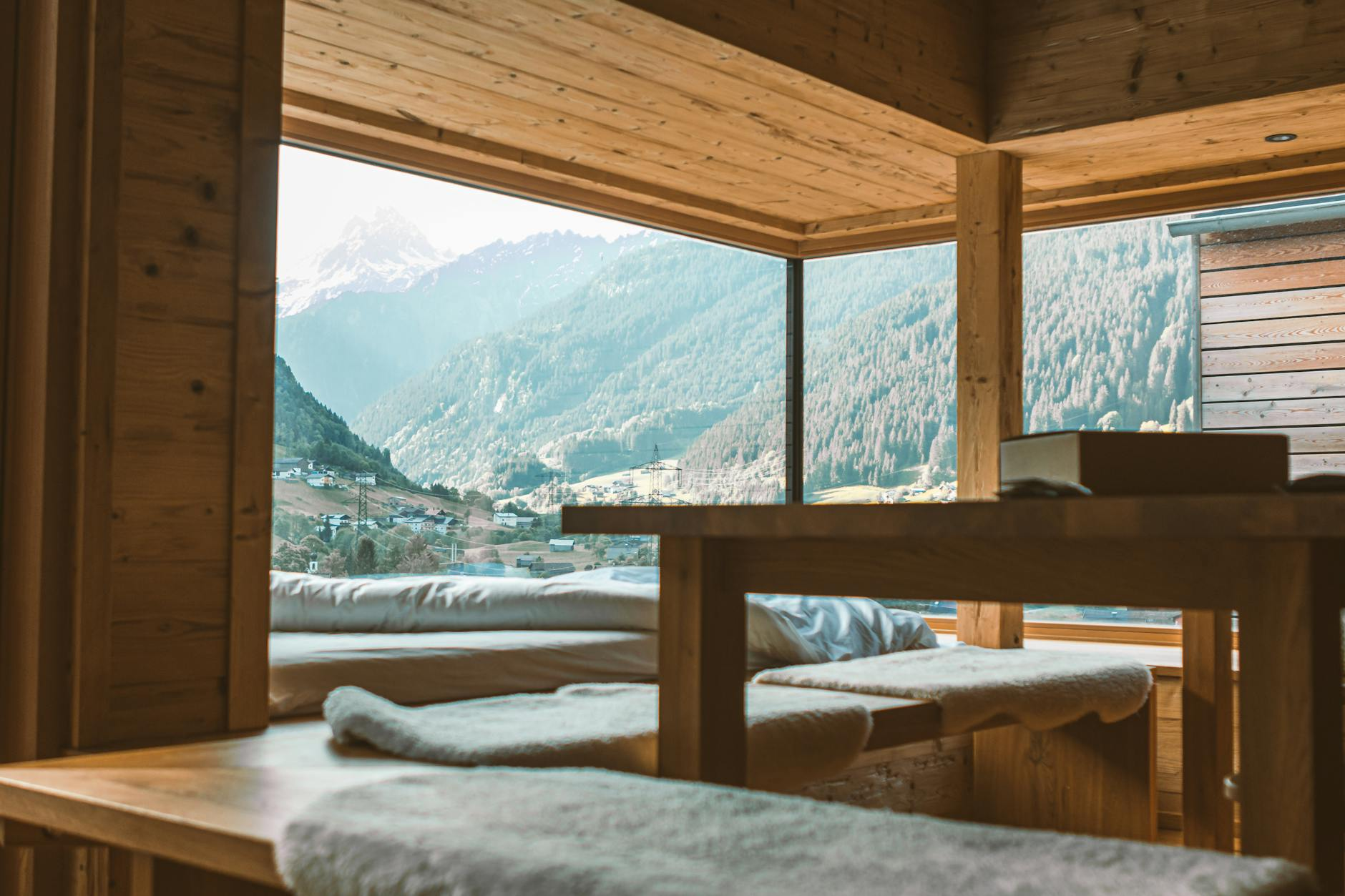 Ein moderner Schweizer Wohnraum mit traditionellen Elementen: Holzbalken an der Decke, Jura-Kalkstein-Boden und zeitgemässen Möbeln in natürlichen Materialien, die den authentischen Schweizer Einrichtungsstil zeigen.