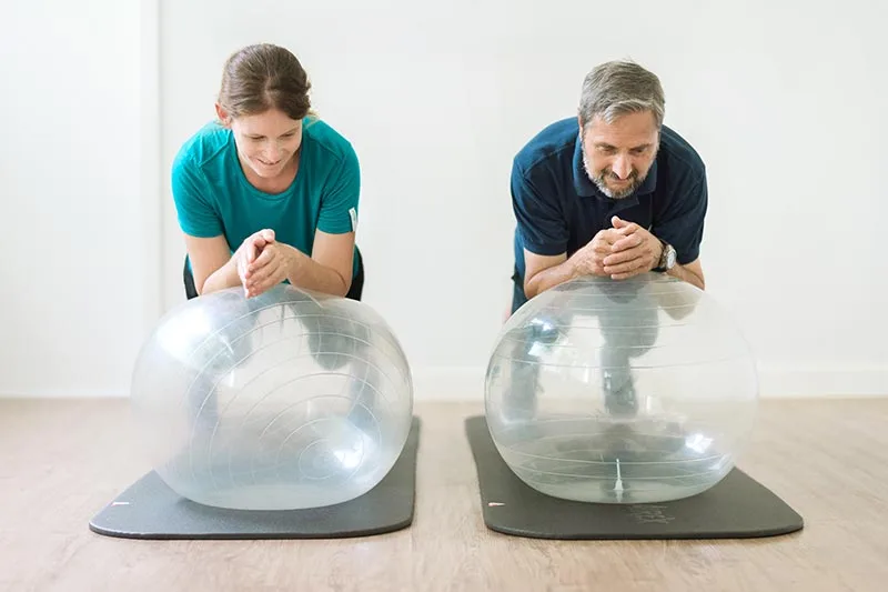 A physiotherapist guides a patient through a cable-machine exercise, showing the hands-on, personalized approach central to Physiowerkstatt's philosophy.