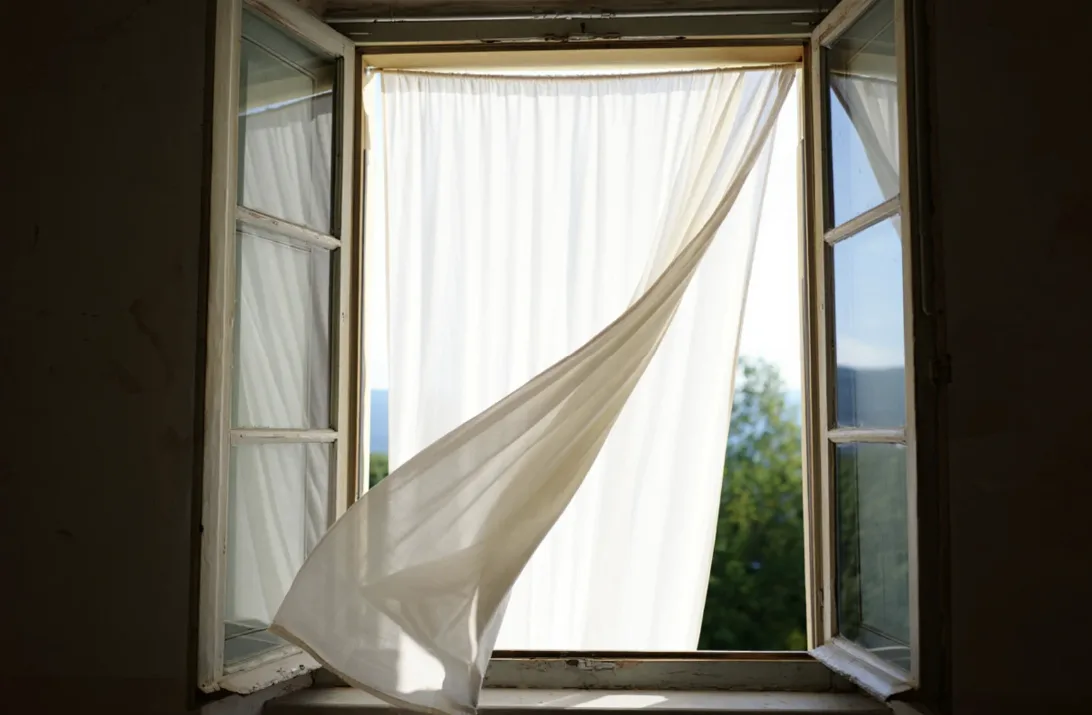 Ein modernes Schweizer Wohnzimmer mit weit geöffneten Fenstern, durch die frische Luft und Tageslicht einströmen, symbolisiert effektives Lüften zur Energieeinsparung und Schimmelprävention.