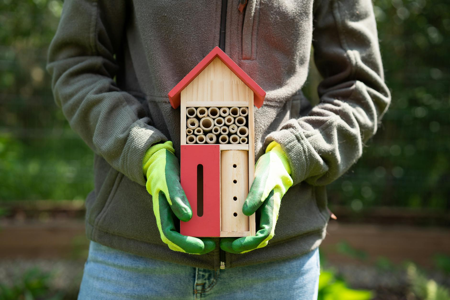Ein winterlicher Schweizer Garten mit verschiedenen tierfreundlichen Einrichtungen: Ein Igelhaus unter Laub, ein Vogelhäuschen mit Körnern, ein Eichhörnchen-Kobel im Baum und ein Insektenhotel an einem Holzpfosten, umgeben von naturnahen Pflanzen.