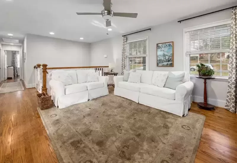 A dirty, stained living room rug with white sofas, showing before-cleaning wear that Lässer's restoration expertise is designed to address.