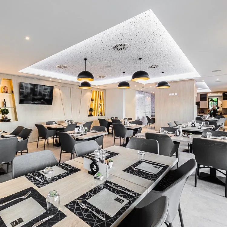 Elegant modern restaurant interior with black pendant lights and neatly set tables.