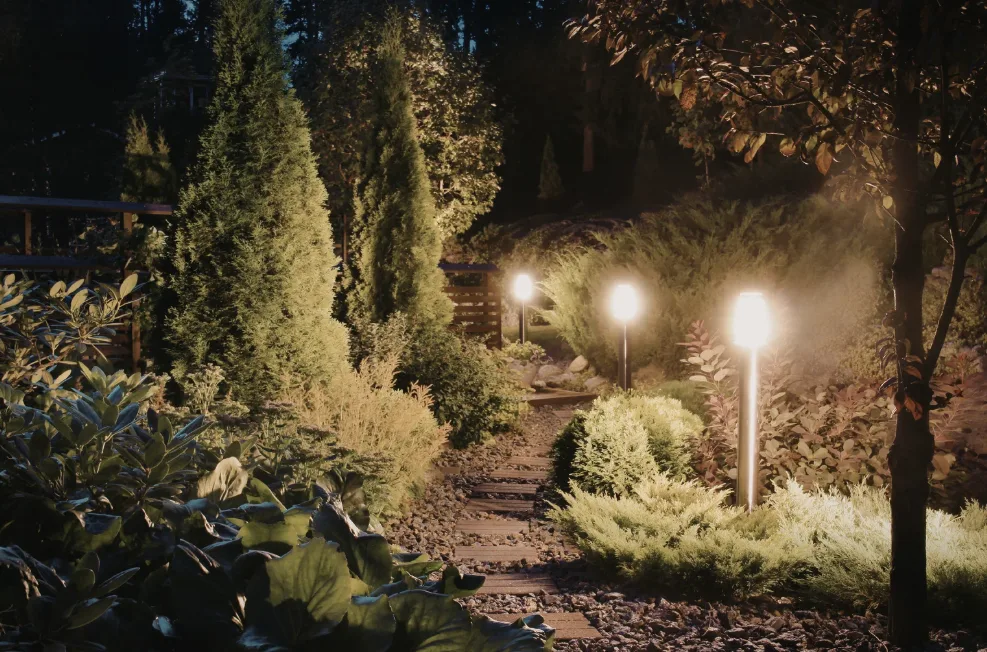 Ein friedlicher Schweizer Garten in der Dämmerung mit warmen, umweltfreundlichen LED-Leuchten, die sanft einen Steinweg und eine Sitzgruppe beleuchten, ohne Lichtverschmutzung zu verursachen.