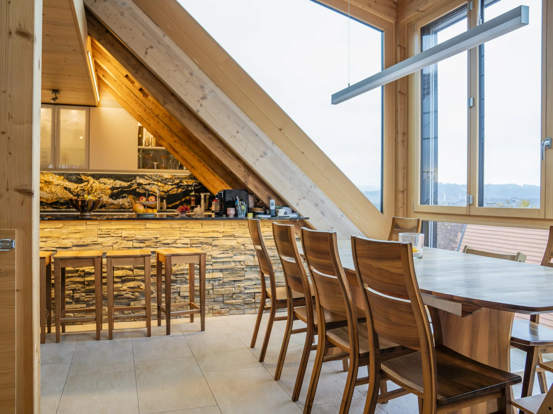 Rustic alpine dining room with timber frame, stone bar backsplash, and walnut furniture.