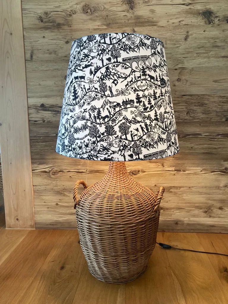 A black-and-white patterned lampshade featuring folk-art silhouettes of deer, trees, and cabins on a floor lamp.