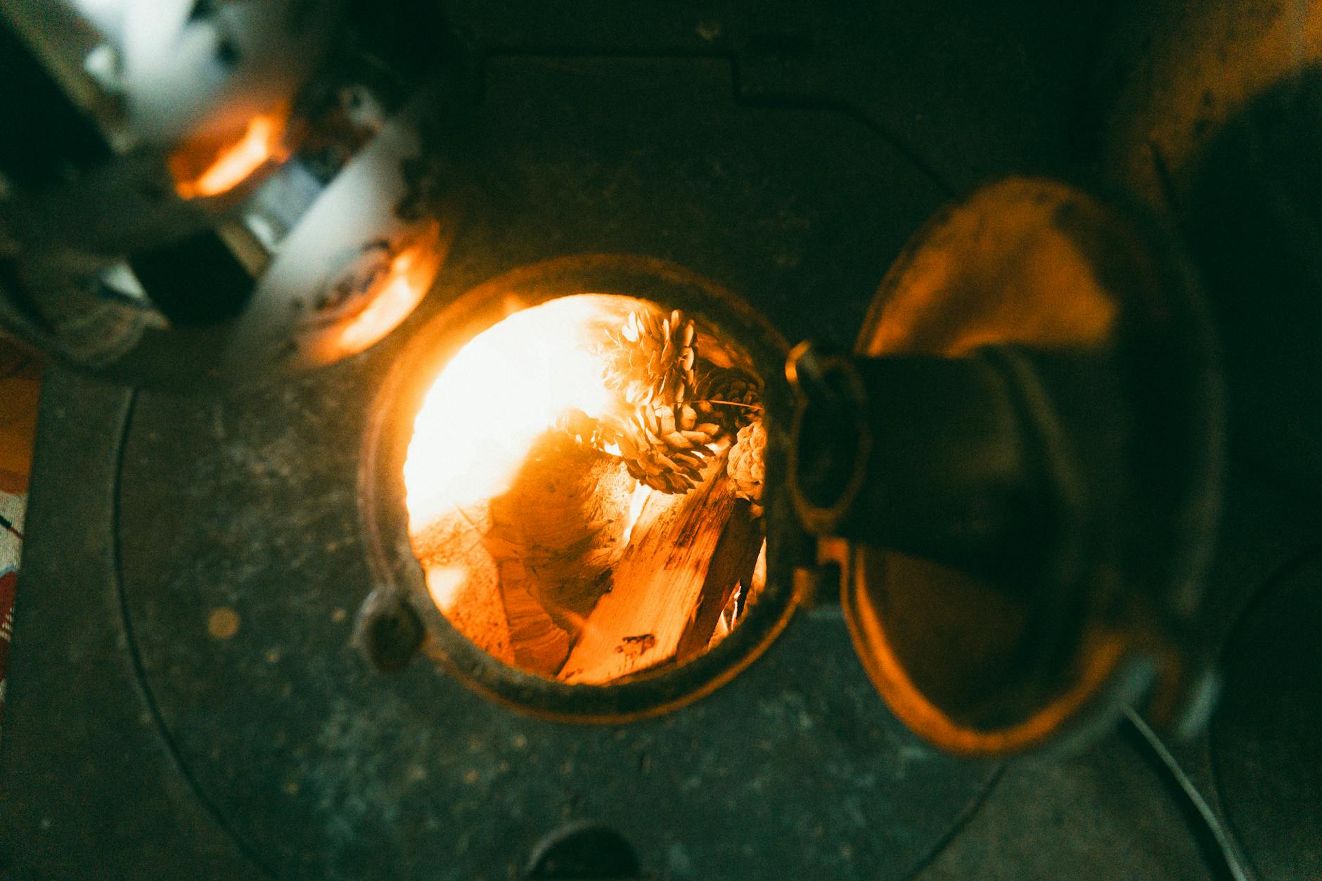 Ein moderner Holzofen in einer schweizerischen Wohnstube mit trockenem Brennholz daneben, symbolisiert umweltfreundliches und gesetzeskonformes Heizen.