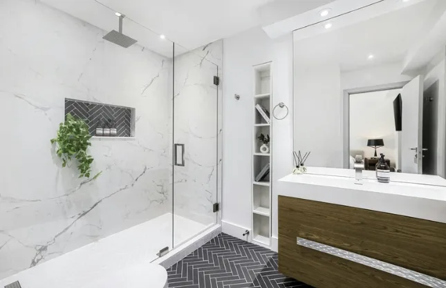 Modernes Schweizer Badezimmer mit bodengleicher Dusche, mattschwarzen Armaturen und schlichten Holzregalen im neutralen Design.
