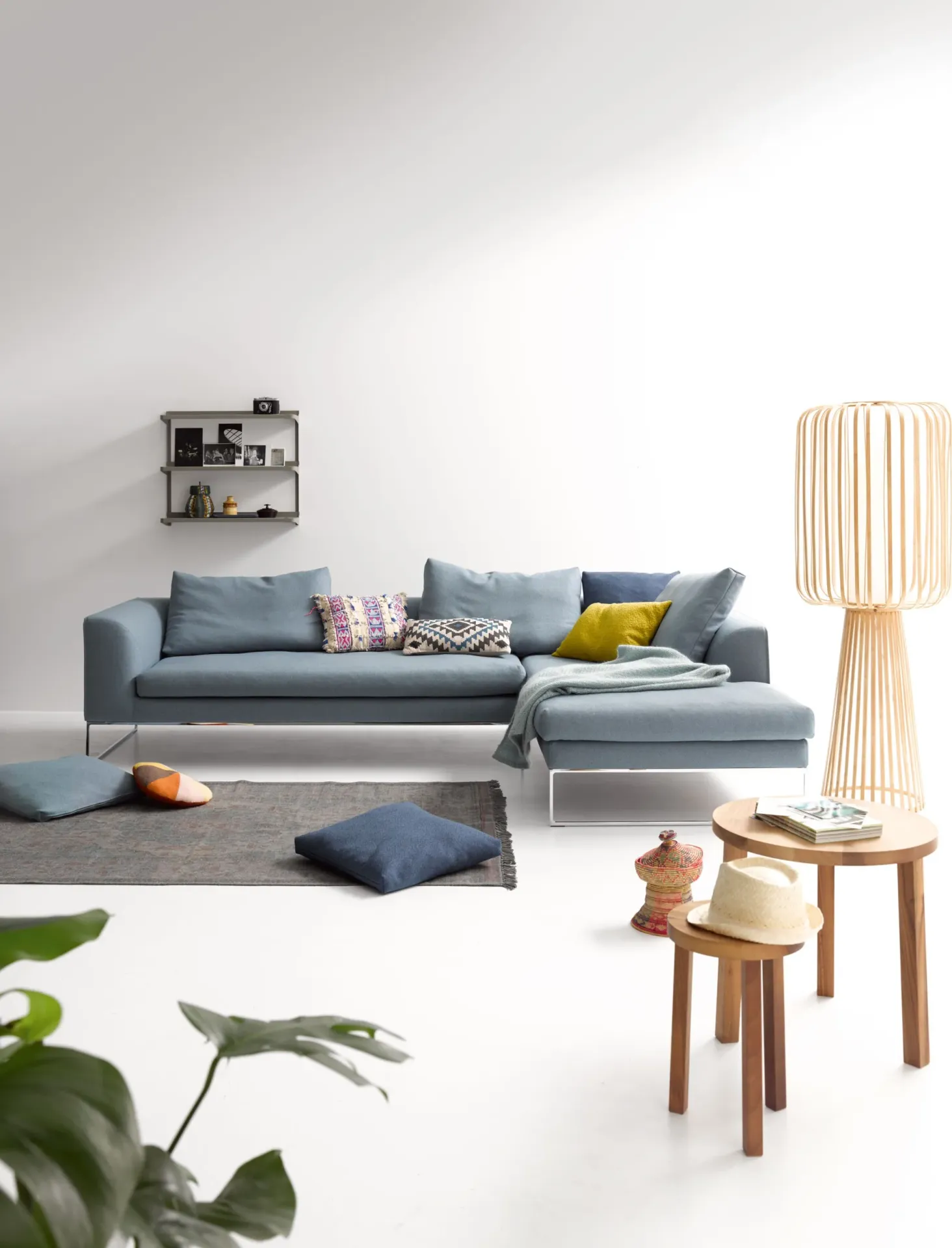 A stylish blue sectional sofa with accent cushions in a clean Scandinavian-inspired living space.