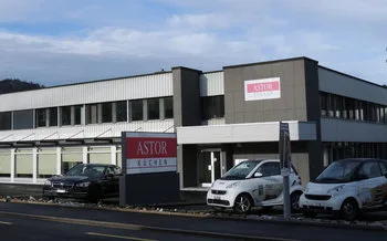 Exterior view of the ASTOR Küchen showroom building with parked cars out front.